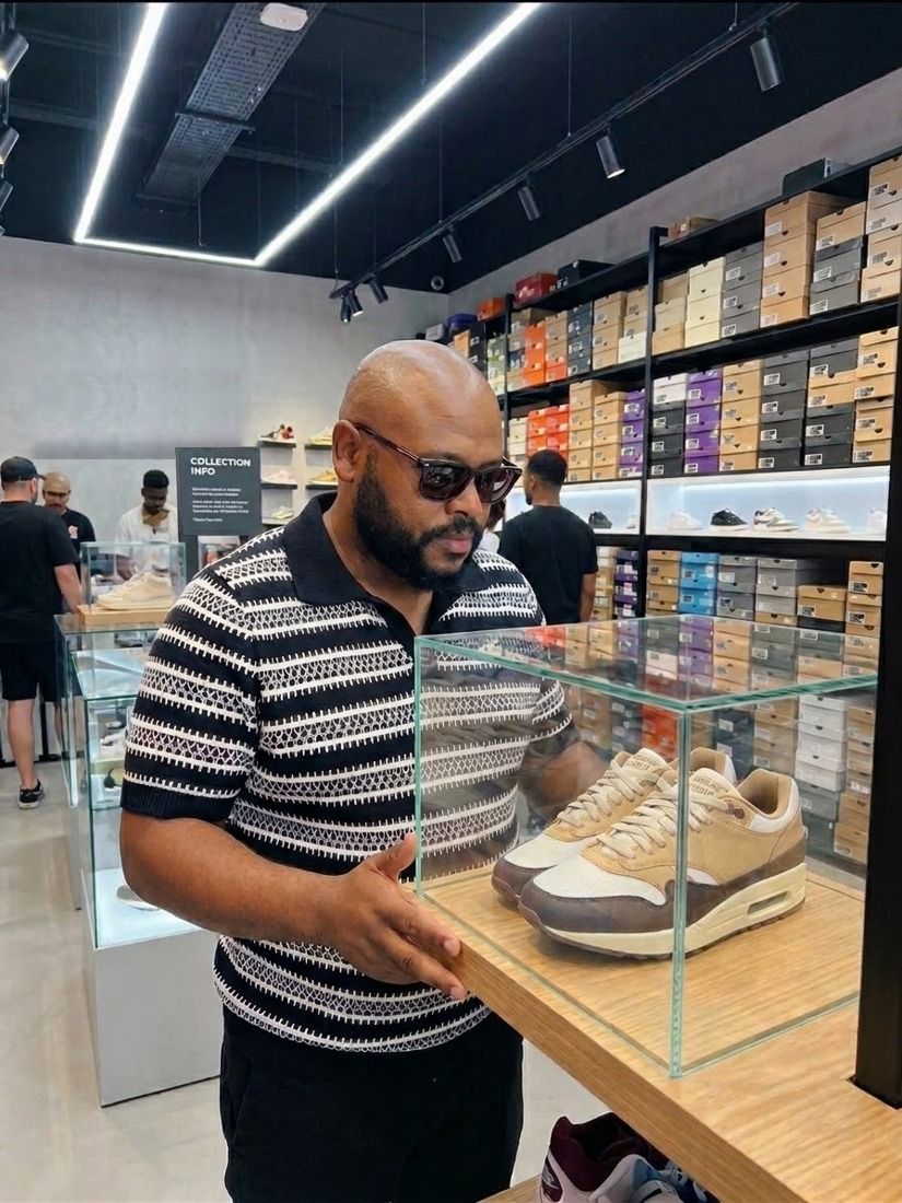 A shopper studies a pair of sneakers in a glass display case in a shoe shop